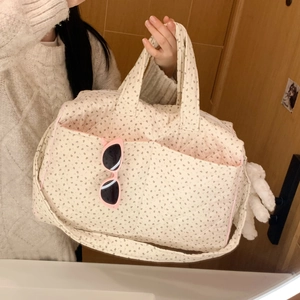 Detailed shot of floral quilted tote bag with side pocket and plush charm accessory