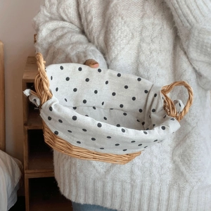 Close-up of woven rattan basket with white polka dot liner and circular handles