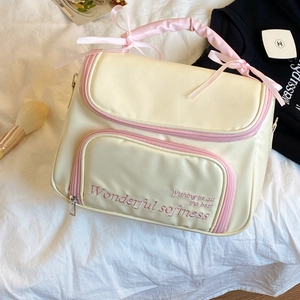 Détail de la trousse de maquillage crème avec broderie rose et poignée à nœud élégante