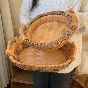 Detail of two-piece nesting hand-woven trays with wooden handles and rivet fixings