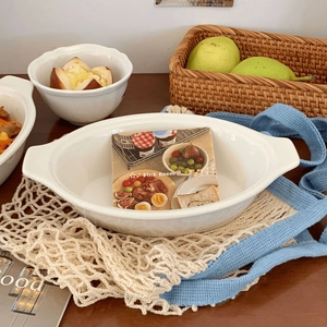 Detail view of white ceramic oval baking dish with handles on rustic woven background
