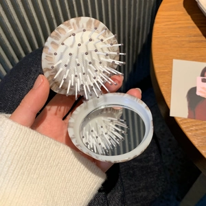Close-up of leopard print folding hairbrush with integrated makeup mirror for travel