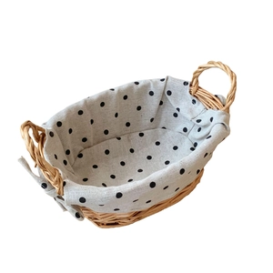 Oval hand-woven wicker storage basket with polka dot fabric lining and round handles