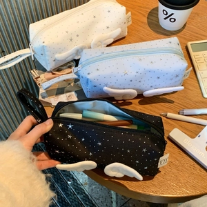 Detailed view of angel wing stationery bags in various colors on a wooden desk