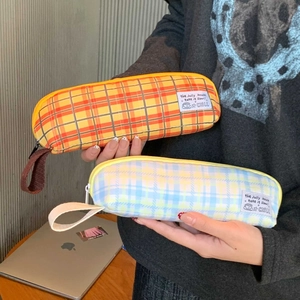 Detail of checkered canvas pencil case with a side handle strap and woven label