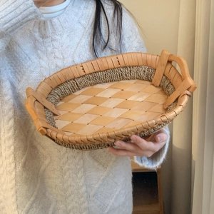 Handheld view of a woven wicker storage tray with sturdy wooden handles and natural texture