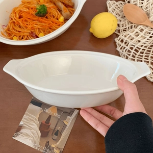 Close-up of white ceramic oval salad bowl with handles in a warm lifestyle home setting