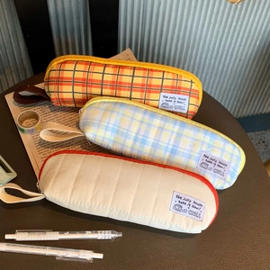 Detail of plaid and quilted pencil cases with zippers on a vintage stationery desk