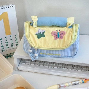 Close-up of blue plaid pencil case with yellow flap and colorful butterfly embroidery