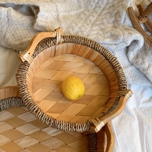 Detailed top view of a handmade woven bamboo tray with a lemon and wooden handles