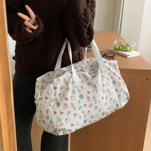Detail of a large white canvas travel bag with Hello Kitty patterns and double handles