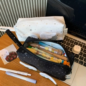 Star wing pencil case with silver star patterns and 3D plush wings on wooden desk