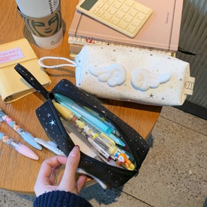 Detail of star pattern pencil case with 3D angel wings on a cozy wooden desk setup