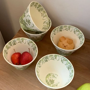 Detail shot of ceramic lily valley bowls with green floral print on a wooden table