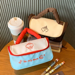 Detail of The Jolly House makeup bag with cartoon embroidery and dual zipper closure