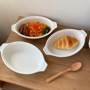 Detail view of a white ceramic oval baking dish with handles for salad and pasta