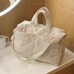 Close-up of quilted floral tote bag with dual handles and shoulder strap on bathroom counter