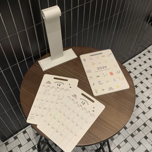 Macro detail of a 2026 desktop calendar with colorful illustrations on a wooden table