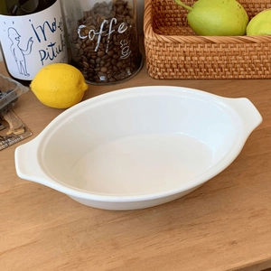 Detailed top view of white ceramic oval baking dish with handles on a rustic wooden table