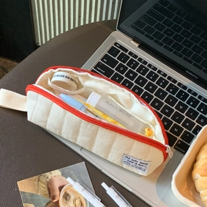 Detailed view of cream quilted pencil case with contrast orange zipper and soft texture