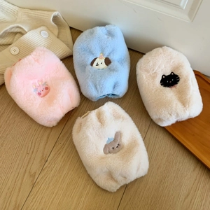 Detailopname van pluizige pluchen tasjes in pasteltinten met schattig borduurwerk