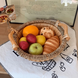 Detail of hand-woven fruit basket with wooden handles and assorted faux pastries