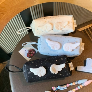 Detailed view of plush wing pencil cases in white, blue, and black with star patterns