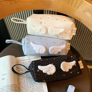 Detailed view of pencil cases with plush angel wings and star patterns in three colors