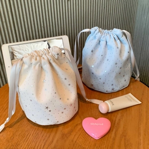Detail of cream and light blue star-patterned drawstring pouches on a wooden table