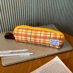 Detail of yellow checkered pencil case with fabric handle and zipper on wood desk