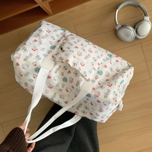 Top view of a spacious Hello Kitty travel bag on a wooden floor with headphones