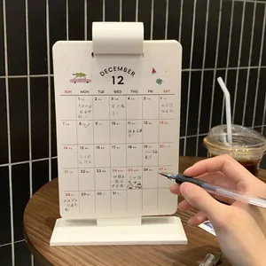 Close-up of minimalist white desktop monthly planner with hand writing on acrylic board