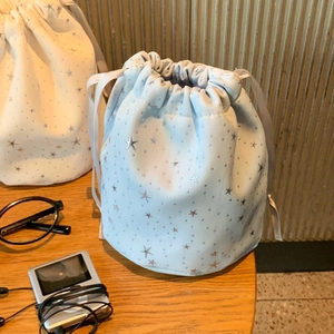 Star pattern drawstring cosmetic bags in light blue and beige on a wooden table