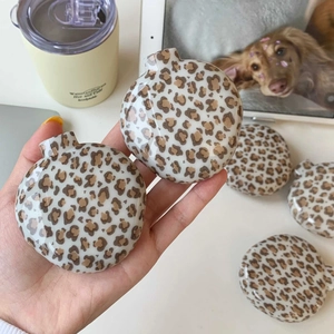 Close-up of leopard print folding hairbrush and portable mirror in a hand-held view