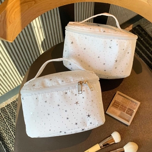 White vanity bag with silver star prints and sturdy top handle for travel storage