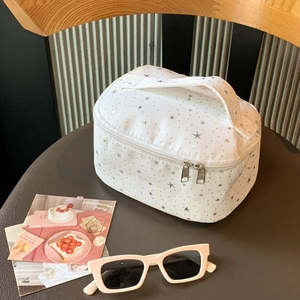 Detail of white star pattern makeup bag with handle and dual zipper closure on a seat