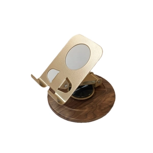 Adjustable golden metal phone stand with a rotating walnut wood base for desktop use