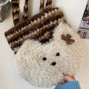 Close-up of knit tote bag with plush bear head decoration and striped texture detail