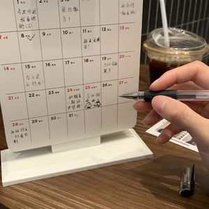 Close-up of minimalist white daily desk calendar with dates and planner grid on wood desk