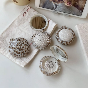 Foldable leopard print hairbrush with mirror shown in open and closed portable positions