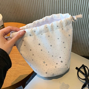 Detail of white drawstring makeup bag with star print showing textured cotton fabric