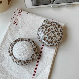 Close-up of leopard print folding hairbrush with massage bristles on a fabric background