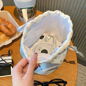 Close-up of white drawstring pouch with silver stars holding an Instax mini camera
