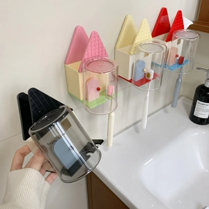 Dettaglio del portaspazzolino a forma di casa a parete con bicchiere e scritta Enjoy Life
