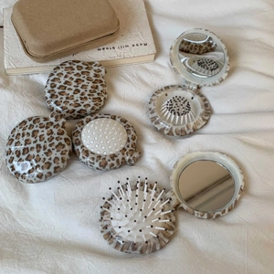Macro view of leopard print folding hairbrush with integrated round makeup mirror