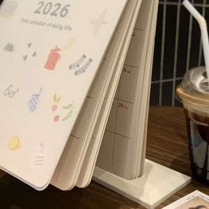 Close-up of 2026 desk calendar with minimalist white stand and artistic daily illustrations
