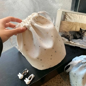 Detail of white star pattern drawstring pouch with textured fabric and satin cords