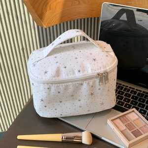 Star pattern makeup bag with handle and dual zippers shown in a desk makeup scene