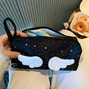 Detail of black pencil case featuring silver star prints and plush angel wings