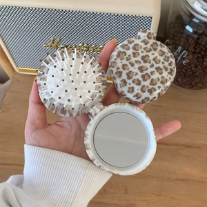 Detail of leopard print folding hairbrush with integrated vanity mirror in hand
